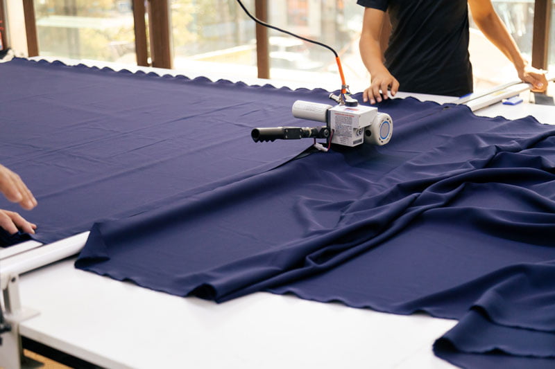person cutting fabric with machine + canvas and upholstery